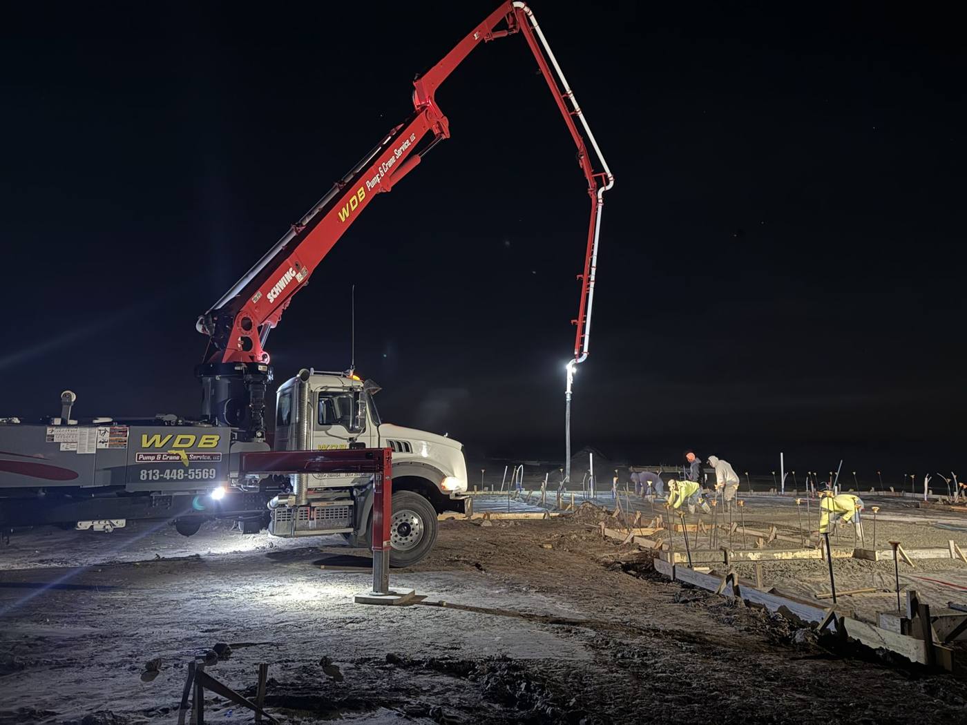 WDB boom pump pouring a slab at night under work lights